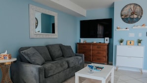 Ein Wohnzimmer mit einer Couch, einem Couchtisch, einem Fernseher und Dekorationselementen.