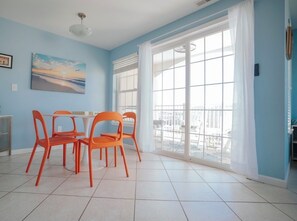 Ein Essbereich mit einem Tisch, vier orangen Stühlen, einem Bild an der Wand und einem großen Fenster mit Vorhängen.