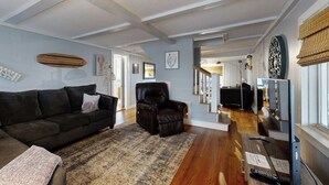A living room with a dark-colored sofa, a leather armchair, a patterned rug, and a television on a stand. - Gorgeous dual-unit, perfect for large groups Dogs are welcome (York)