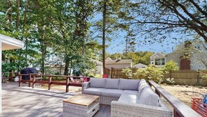 Eine überdachte Terrasse mit einer Couch, zwei Korbstühlen und einer Holzbank.
