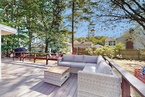 A covered outdoor deck with a sofa, two wicker side tables, and a wooden bench. - Charming York cottage close to beach with firepit & sunroom - dogs welcome (York)