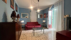 Ein Wohnzimmer mit einem roten Sofa, einem Glastisch, einem Holzschrank, einem Spiegel und einem Fernseher.