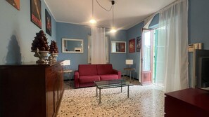 A living room with a red sofa, a glass coffee table, a wooden cabinet, a mirror, and a television. - 106. Oscar, Villa On The Lake (Piemonte)
