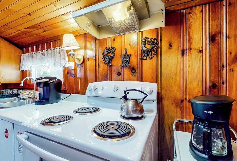 A kitchen with a white stove, a kettle, and a coffee maker.
