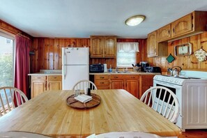 A wooden-paneled kitchen with a refrigerator, microwave, stove, and wooden cabinets.