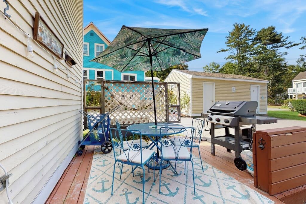 A patio with a table and chairs, a grill, and a wooden chest.