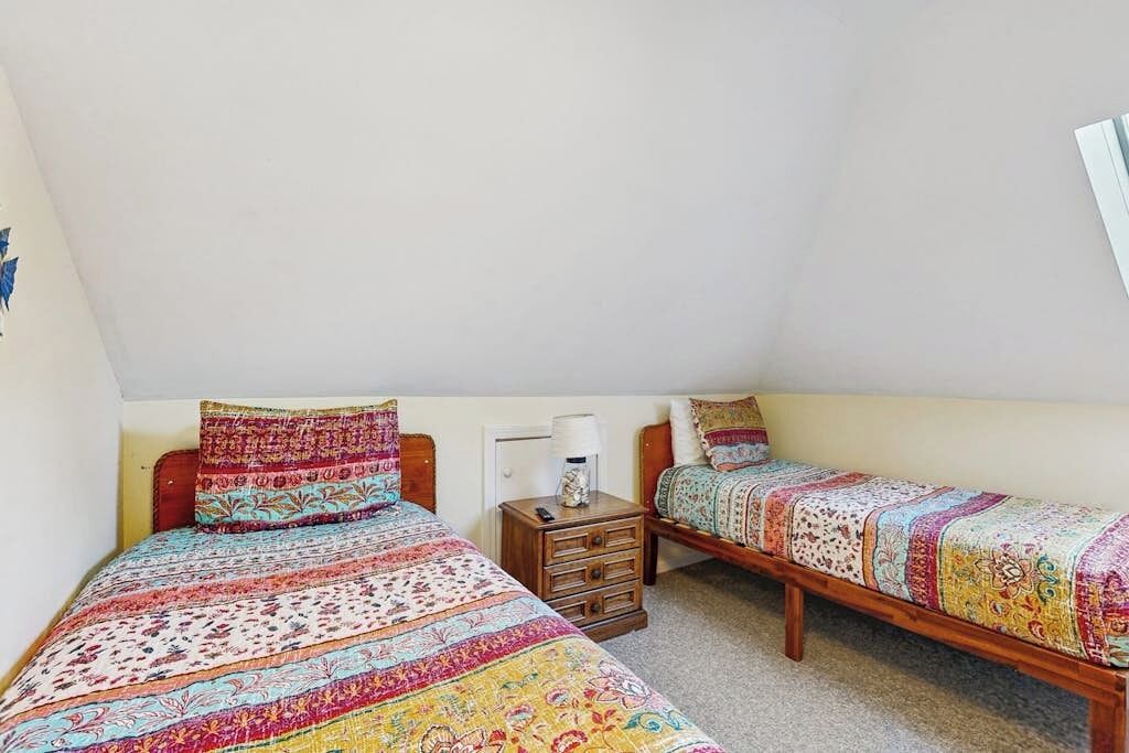 Ein Schlafzimmer mit zwei Einzelbetten, einem Nachttisch mit Lampe und einer kleinen Kommode.