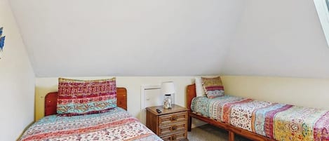 Ein Schlafzimmer mit zwei Einzelbetten, einem Nachttisch mit Lampe und einer kleinen Kommode.