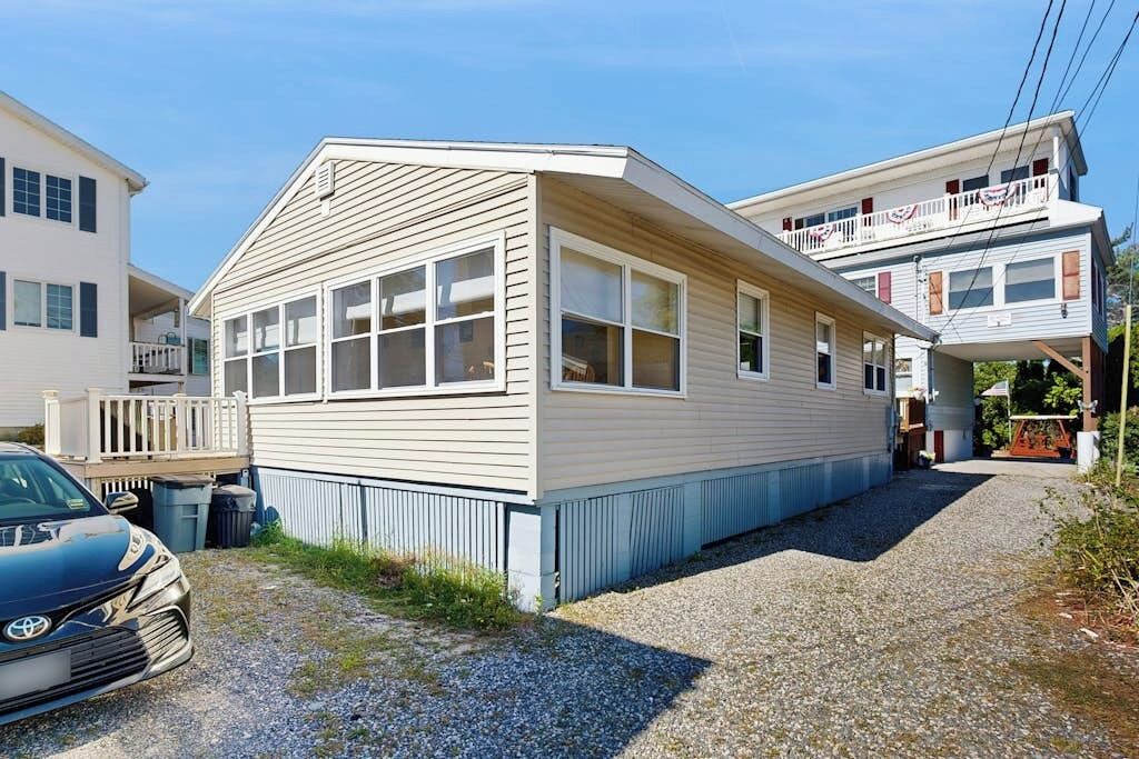 A two-story building with a flat roof, large windows, and a gravel driveway.