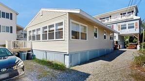 A two-story building with a flat roof, large windows, and a gravel driveway.
