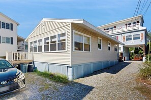 A two-story building with a flat roof, large windows, and a gravel driveway.