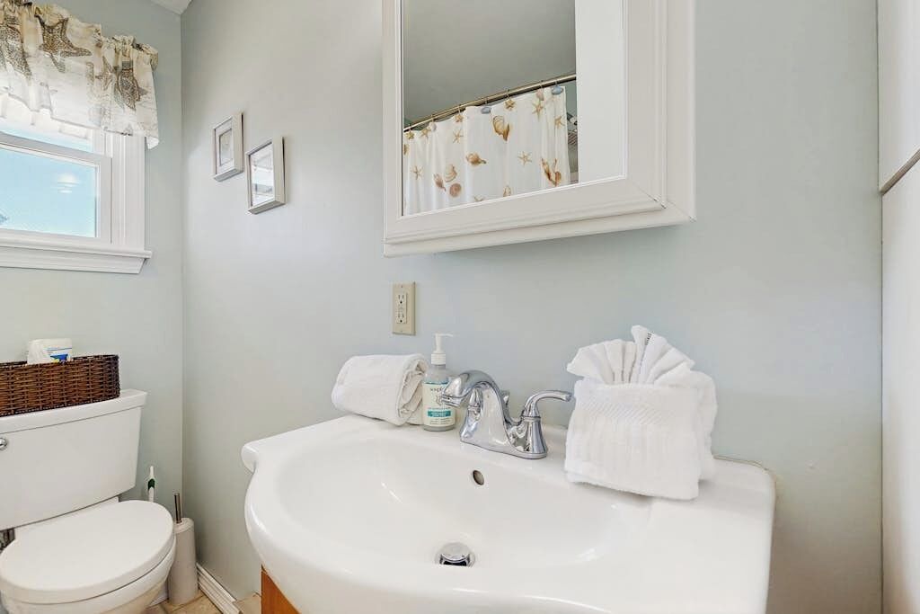 A bathroom with a white sink, a mirror above it, and a toilet.