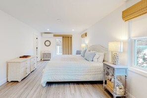 Ein Schlafzimmer mit Bett, Nachttischen, Kommode, Fenster und Tür.