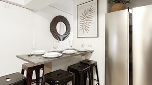 Uma cozinha moderna com uma mesa de jantar posta para quatro pessoas, uma geladeira e um espelho grande.