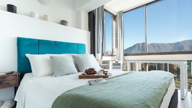 Quarto moderno com cama grande, vista para montanhas e varanda.