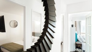 Escada em espiral em quarto moderno de hotel, com cama e uma mesinha.