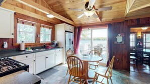 Een houten cabin met een keuken, eethoek en plafondventilator.