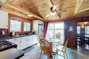 A wooden cabin interior with a kitchen, dining area, and a ceiling fan. - Charming lakefront cottage with a dock, WiFi, & washer/dryer - dogs welcome (Windham)