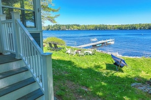 A wooden deck with outdoor seating, a dock, and a view of a lake. - Charming lakefront cottage with a dock, WiFi, & washer/dryer - dogs welcome (Windham)