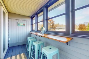 A kitchen with a wooden countertop, bar stools, and large windows.