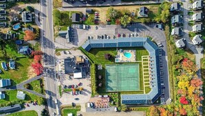 An aerial view of a residential area with a large sports complex, including a tennis court and a swimming pool. - Updated condo 1 mile to beach w/pool, hot tub, tennis & access to EV chargers! (Wells)