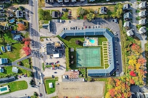 An aerial view of a residential area with a large sports complex, including a tennis court and a swimming pool. - Updated condo 1 mile to beach w/pool, hot tub, tennis & access to EV chargers! (Wells)