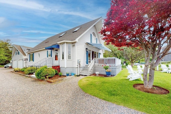 A two-story house with a front porch, a driveway, and a well-maintained lawn. - Charming home with ocean view, firepit, deck, golf nearby, & W/D (York)