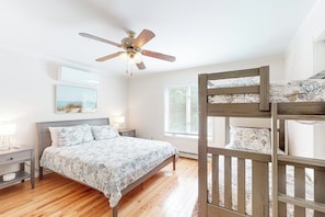 A bedroom with a bunk bed, a ceiling fan, a bedside table with a lamp, and a window with blinds. - Charming home with ocean view, firepit, deck, golf nearby, & W/D (York)