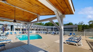 Un espace piscine avec des chaises longues et une terrasse en bois.