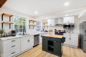 A modern kitchen with white cabinets, a central island, and a stainless steel refrigerator.