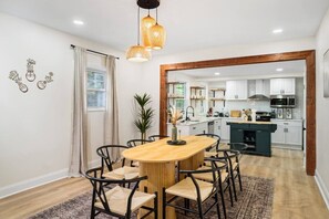 A modern kitchen with white cabinets, a wooden dining table, and black chairs.