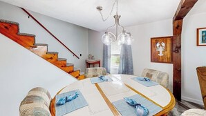 A dining area with a round table, chairs, and a staircase with wooden steps. - Adorable nautical home close to town, W/D, & streaming, dog friendly (Wells)