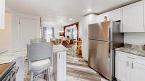 A modern kitchen with white cabinets, a stainless steel refrigerator, and a marble countertop. - Adorable nautical home close to town, W/D, & streaming, dog friendly (Wells)