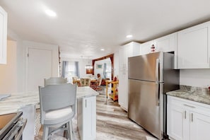 A modern kitchen with white cabinets, a stainless steel refrigerator, and a marble countertop. - Adorable nautical home close to town, W/D, & streaming, dog friendly (Wells)