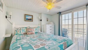 Ein Schlafzimmer mit einem Bett, einem Deckenventilator, einem Fenster mit Ausblick und einer Kommode.