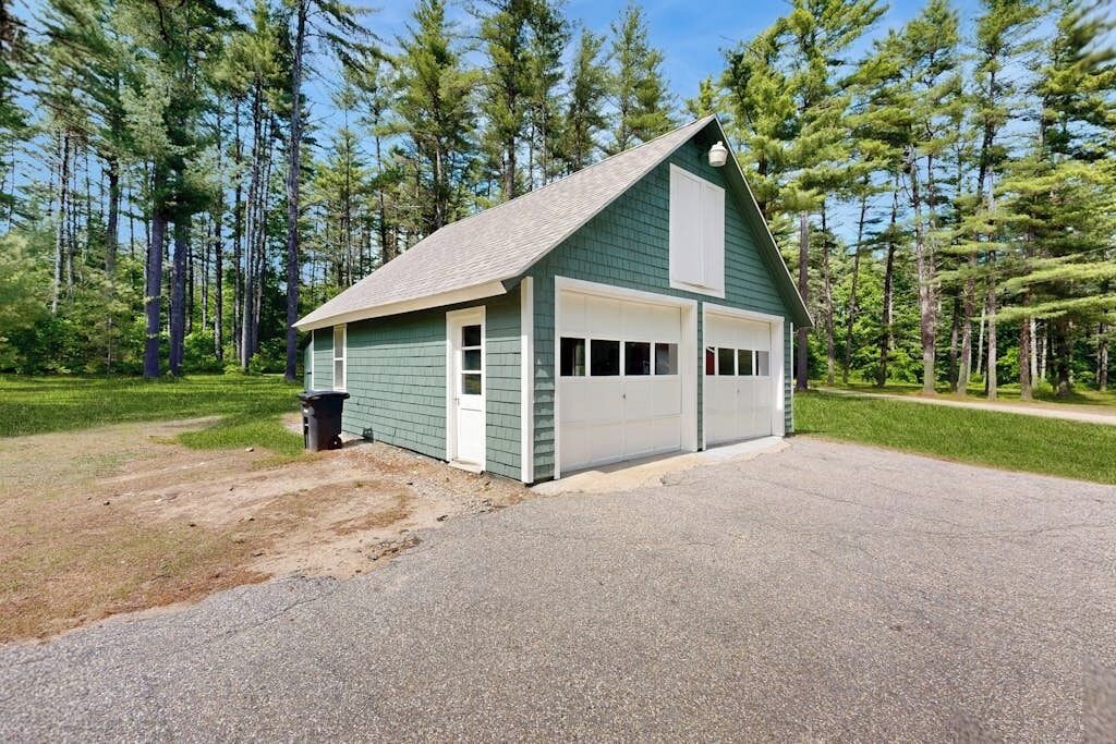 Ein eingeschossiges Gebäude mit Garage, umgeben von einem Wald.