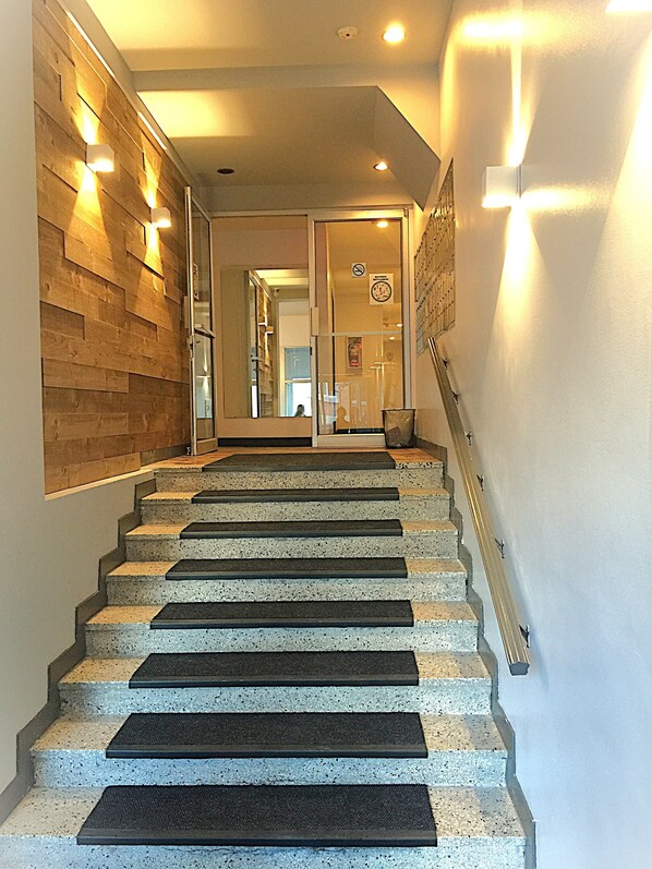 Eine Treppe mit Handlauf, Holzvertäfelung und einer Tür mit Rauchverbot-Hinweis.