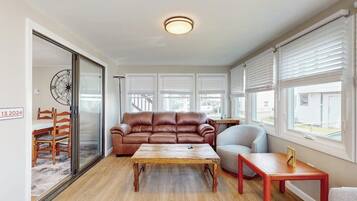 A modern living room with a leather sofa, a wooden coffee table, and a red side table.