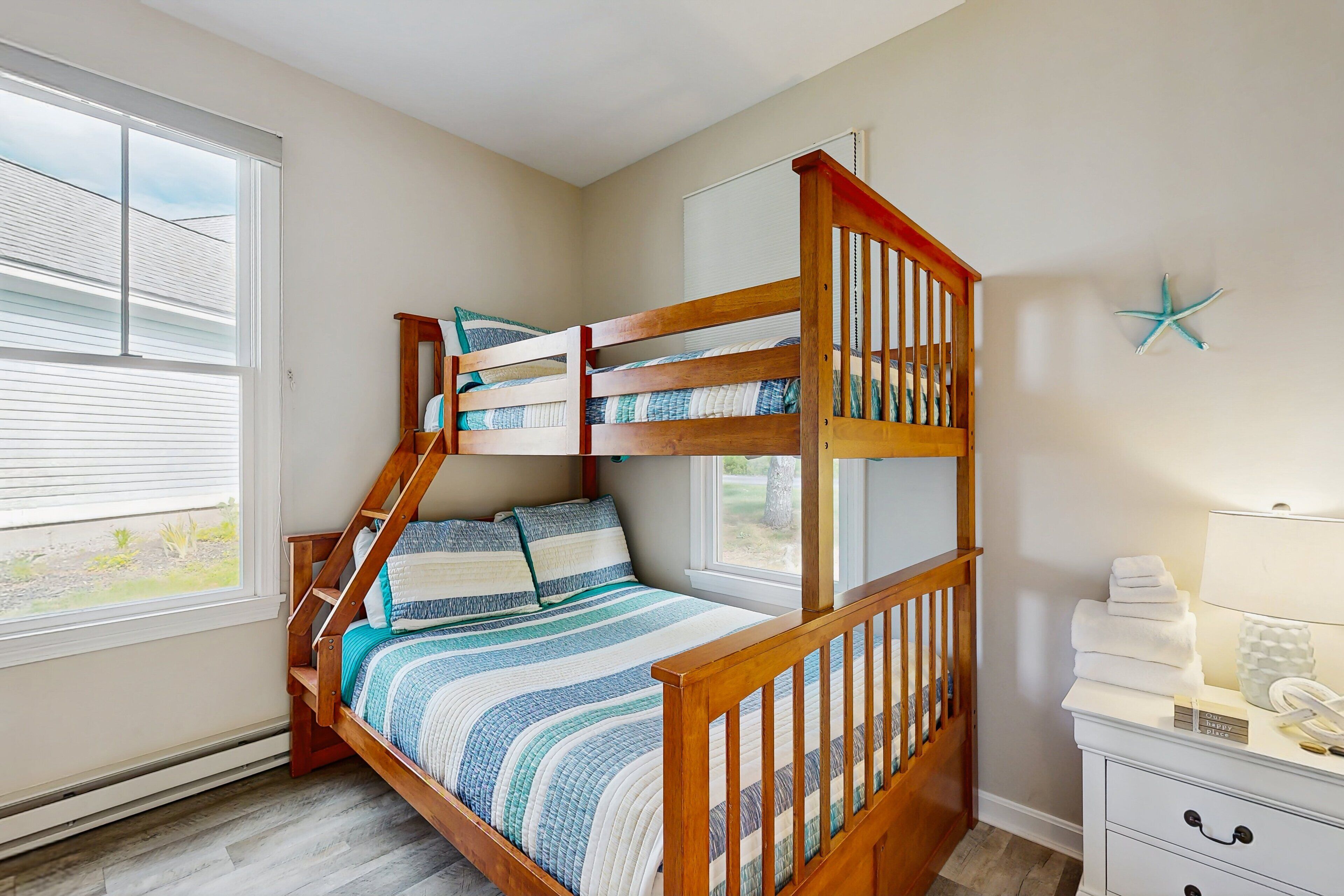 A bunk bed with a wooden frame, a bedside table with a lamp, and a starfish decoration on the wall.