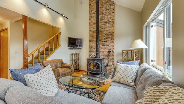 A cozy living room with a sofa, a glass coffee table, a fireplace, and a television. - Beautiful townhome w/ mountain views from the deck, near skiing (Bartlett)