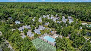 Vue aérienne d’un quartier résidentiel avec des maisons, un court de tennis et une piscine.