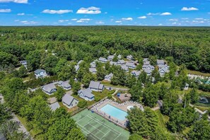 An aerial view of a residential area with houses, a tennis court, and a swimming pool. - Cozy cottage with steps-to-the-pool access, fully equipped kitchen & beach gear (Wells)