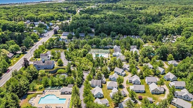 Vue aérienne d’un quartier résidentiel avec des maisons, une piscine et une route.