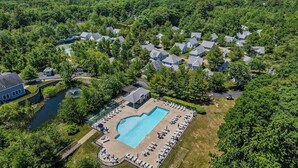 Vue aérienne d’un quartier résidentiel avec des maisons, une piscine et un petit plan d’eau.