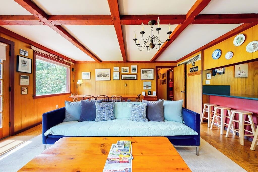 Una habitación acogedora con un sofá azul, paredes de madera, techo de madera y una araña.