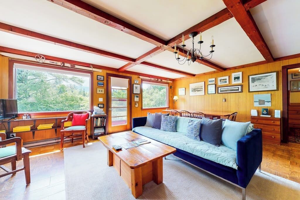 Une pièce chaleureuse avec un plafond en bois, un canapé, une table basse et des tableaux encadrés aux murs.
