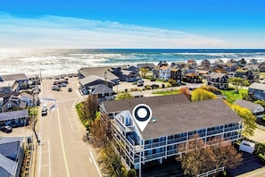 A coastal residential area with houses, a road, and a view of the ocean. - Coastal Wells Beach Condo | Walk to the Ocean | Family-Friendly (Wells)