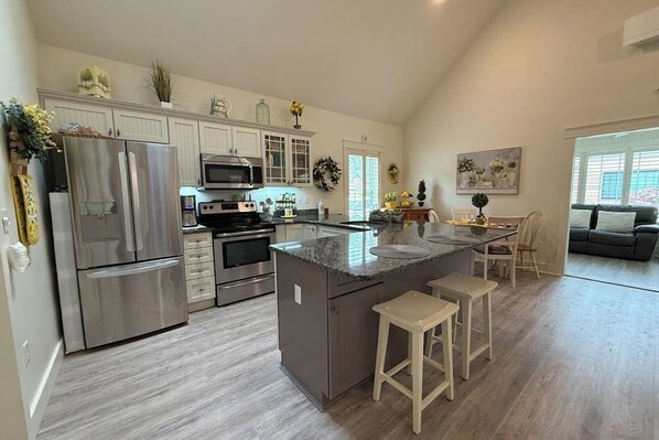 A modern kitchen with stainless steel appliances, a central island, and a dining area with a couch.