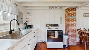 A kitchen with a white stove, a sink, and a brick wall. - Quaint Cottage with Lobster Pot, Modern Amenities, and Several Beaches Nearby (Wells)