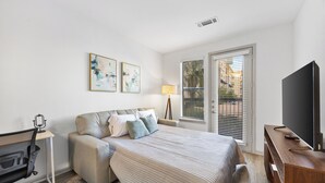 Ein Schlafzimmer mit Bett, Schreibtisch, Stuhl, Fernseher und Bildern.